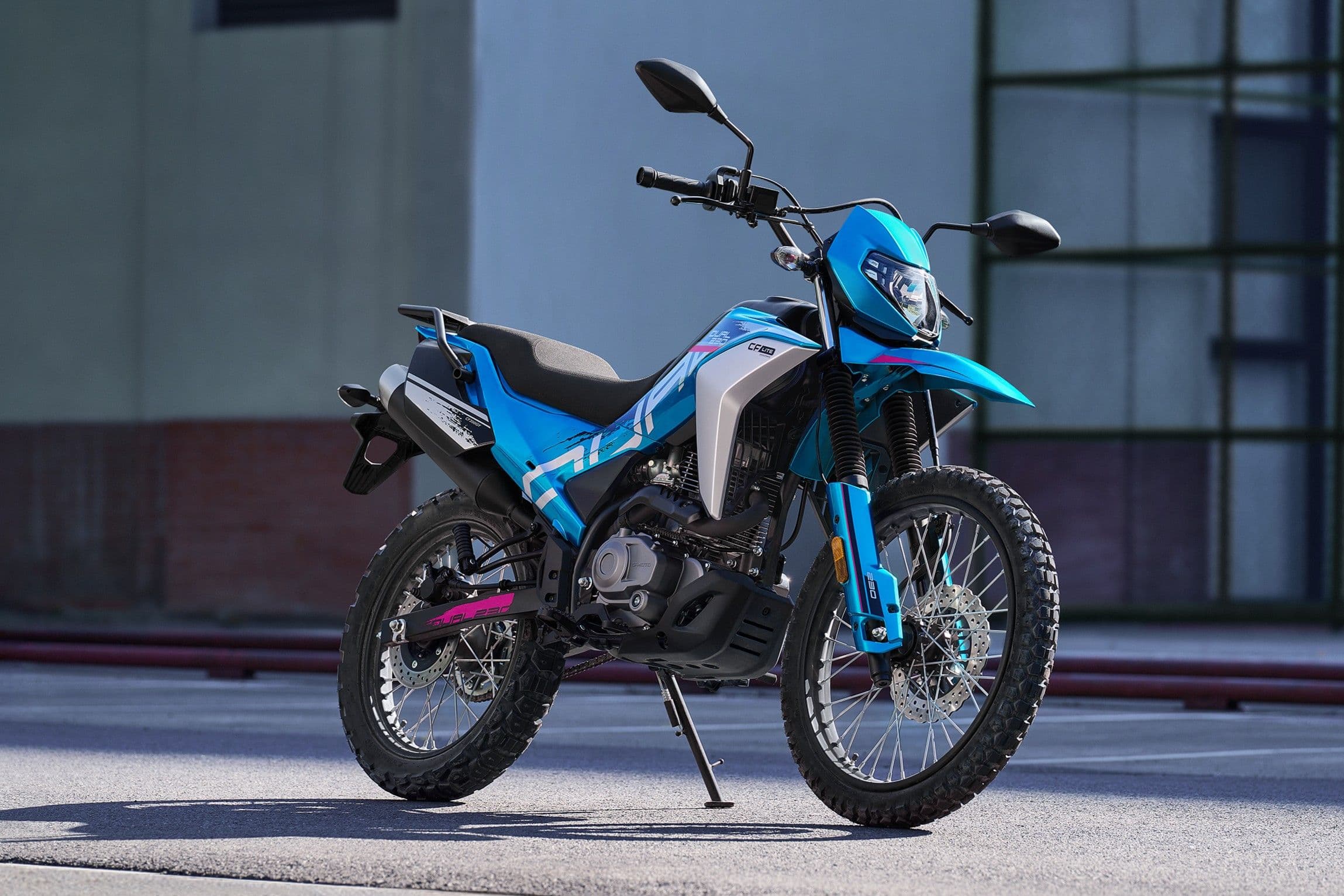 Blue and white dirt bike with knobby tires parked on concrete outdoors.